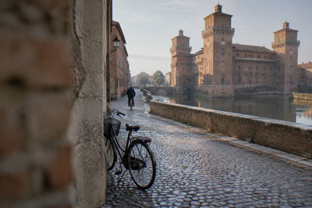 A bicycle leaning against a stone wall beside a cobbled street