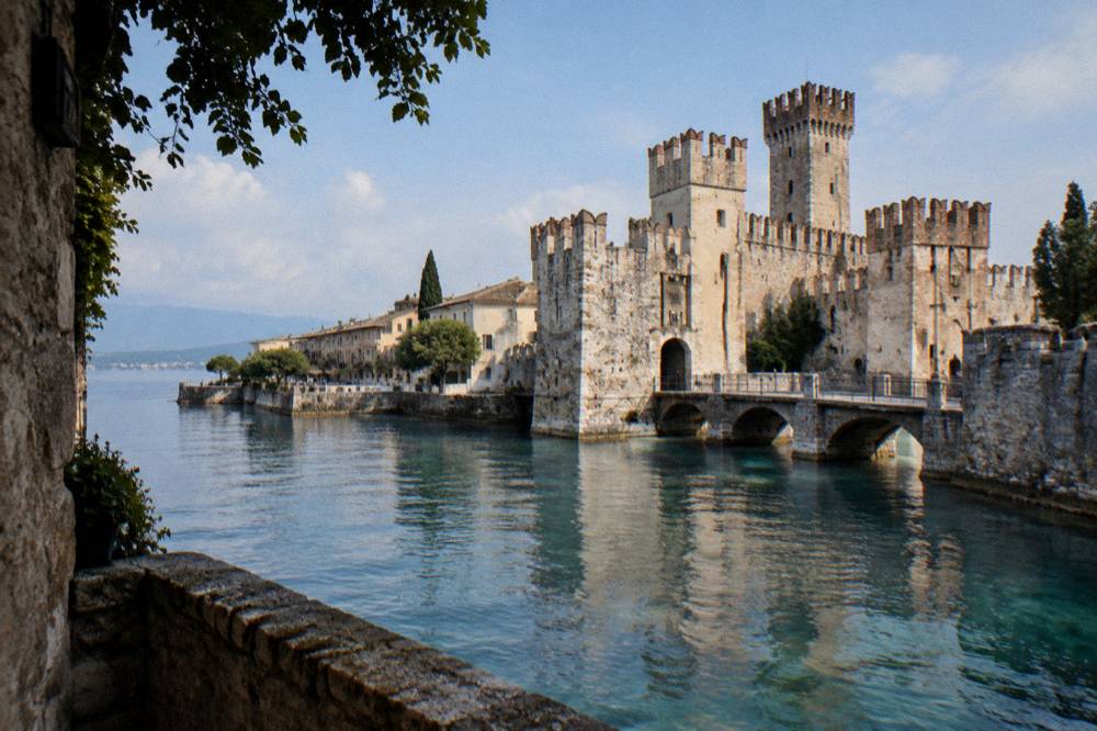 An old stone bridge over a river with a historic city skyline behind it