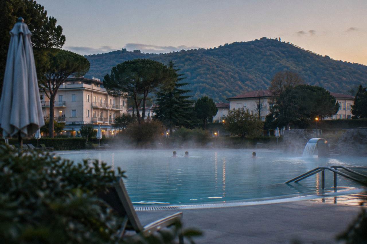 Thermal spa town buildings at the foot of green wooded hills on a clear afternoon
