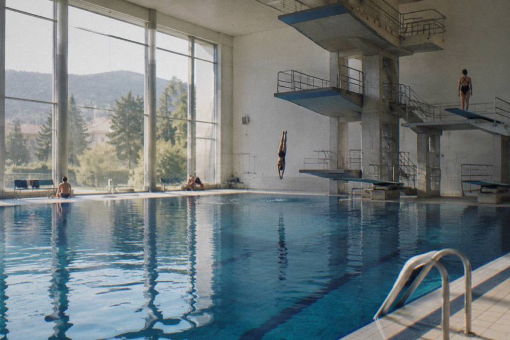 A deep indoor diving pool seen from the deck with divers' platforms above the water