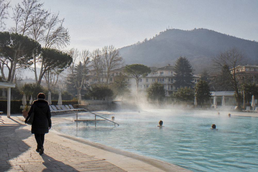 Outdoor thermal pool with steam rising over the water on a cold clear winter morning