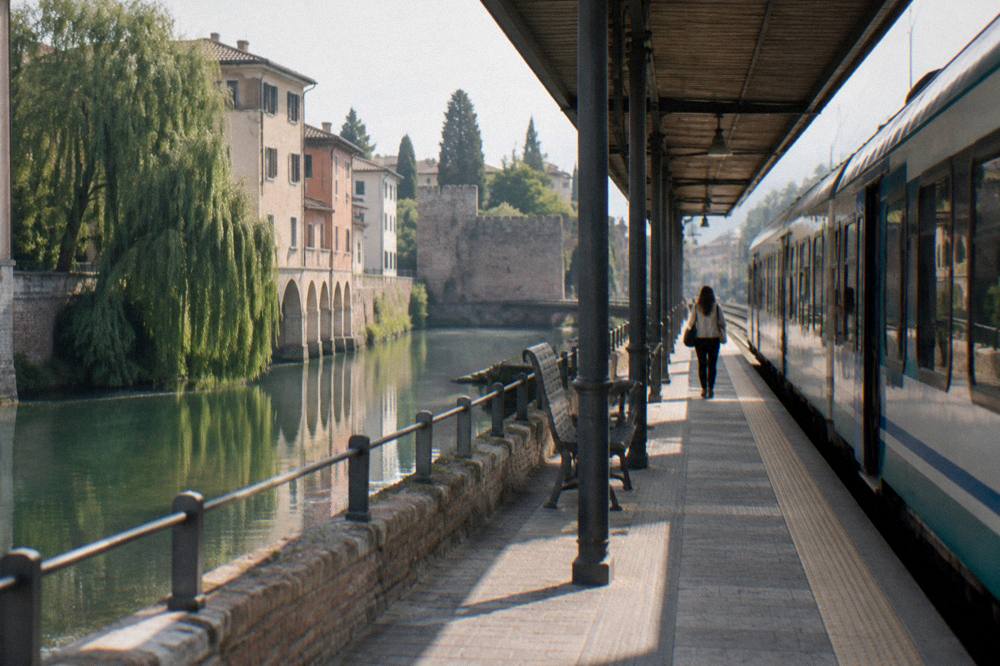 A train platform in northern Italy with a regional train waiting beside a timetable board