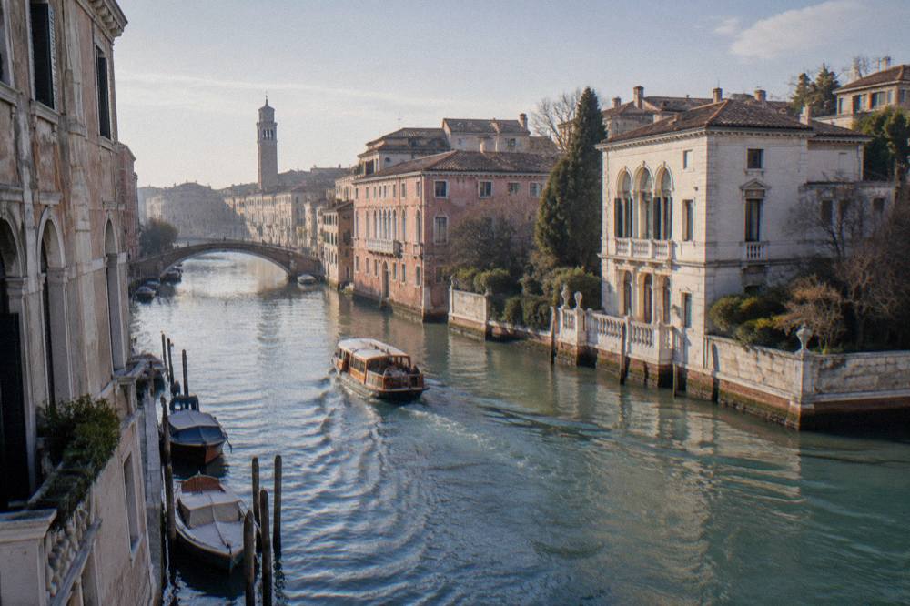 A small passenger boat cruising a calm river past a classical riverside villa