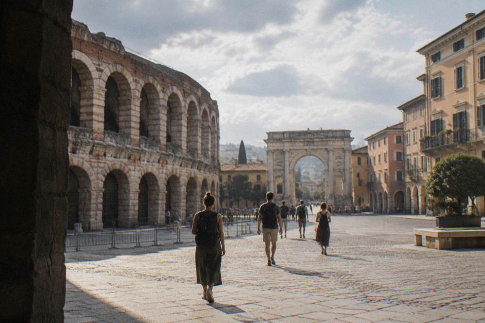 Travellers with backpacks walking through a sunlit Italian piazza toward a Roman arch