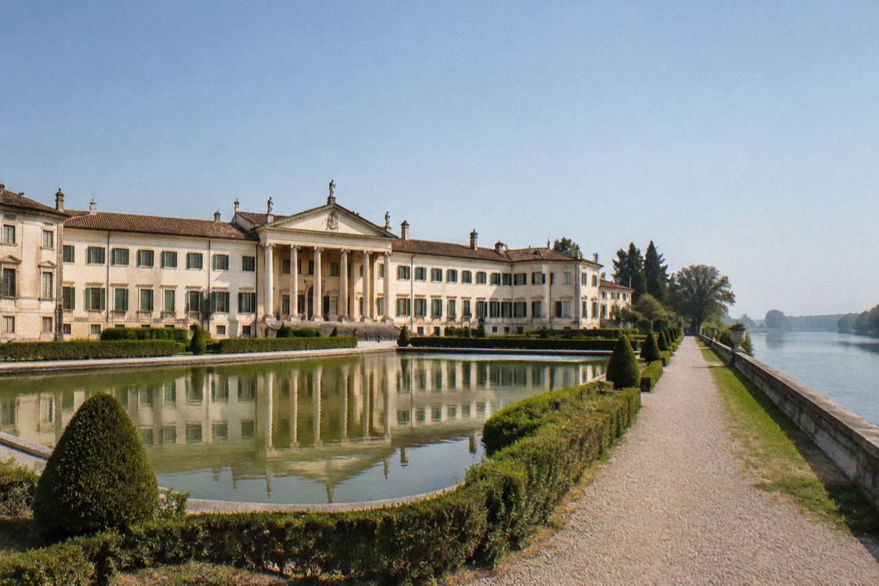A long classical villa facade with rows of green shutters beside a wide river