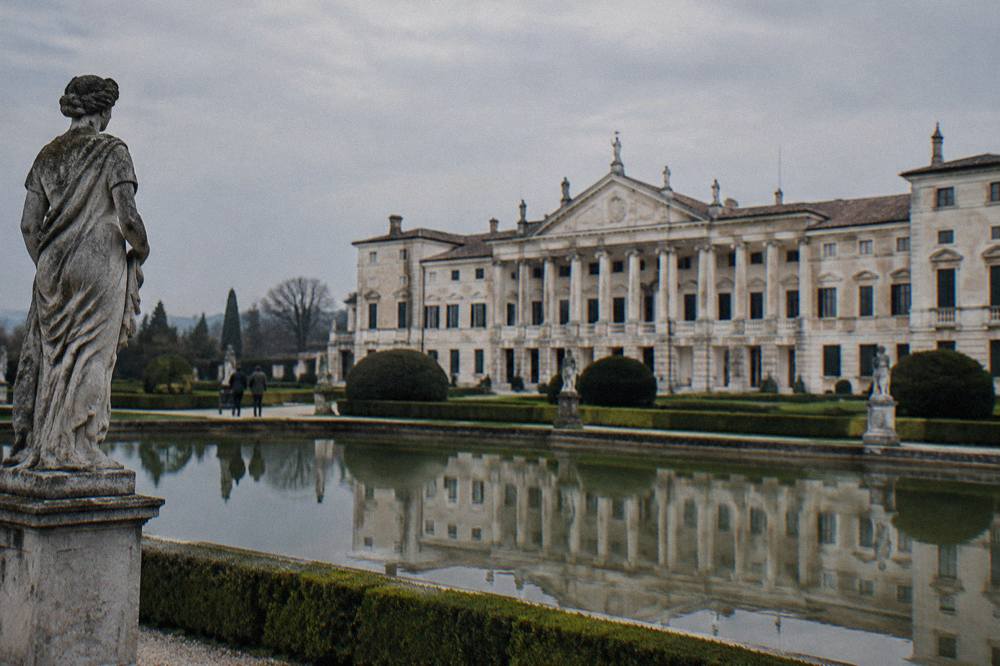 A formal Italian garden with clipped hedges and statues in front of a villa
