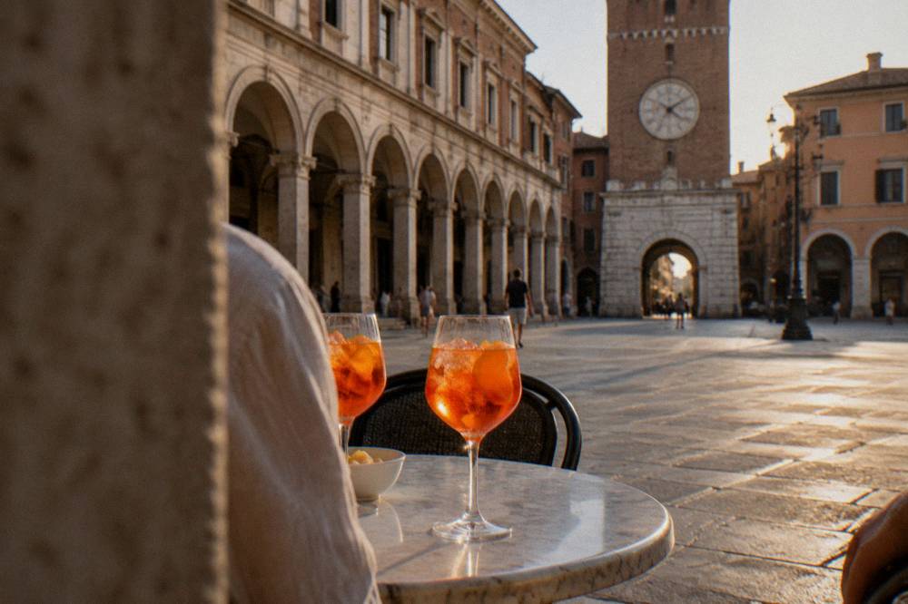 Orange spritz cocktails in wine glasses on a marble table in an Italian square at dusk