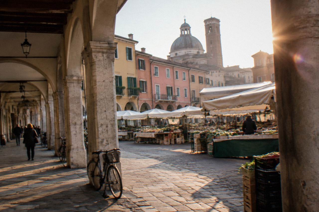 Arcaded street in central Padua with market stalls and historic buildings in soft daylight