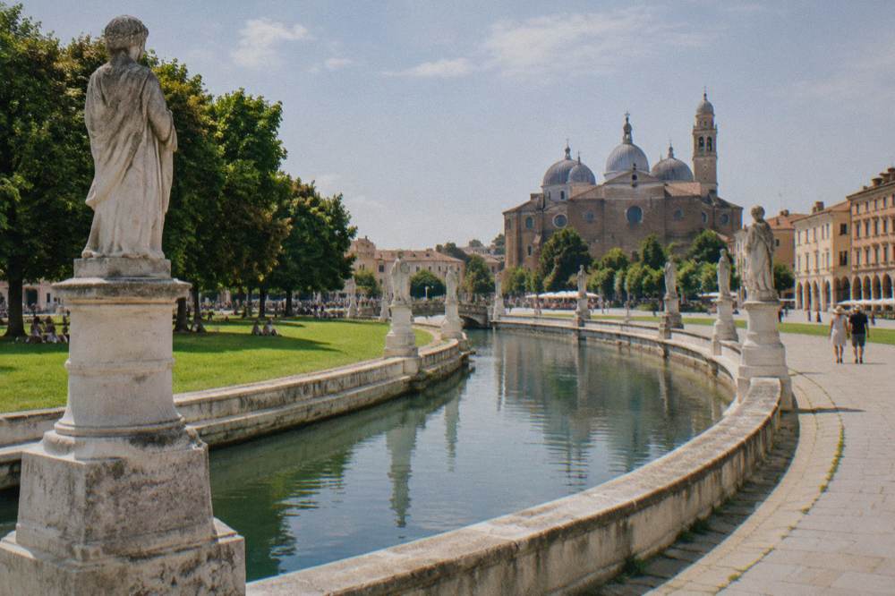 The oval square of Prato della Valle in Padua with its canal ring of statues under a summer sky