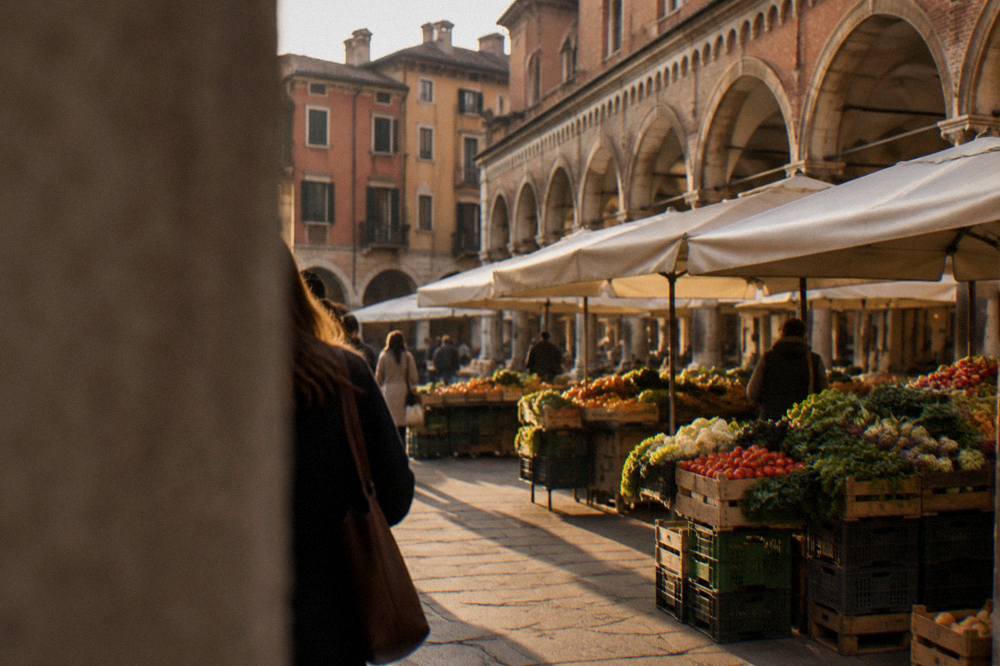 Market stalls with fresh produce under the arcades of Piazza delle Erbe in Padua
