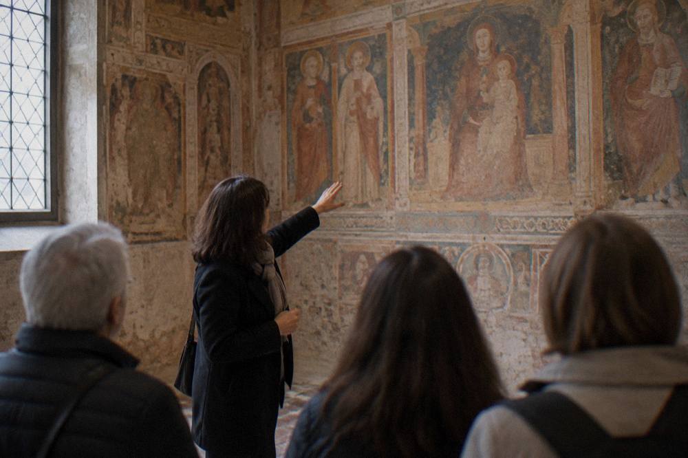 A guide showing a small group a frescoed chapel interior