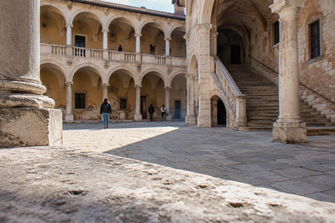 A historic university courtyard in Padua with arched loggias and worn stone steps