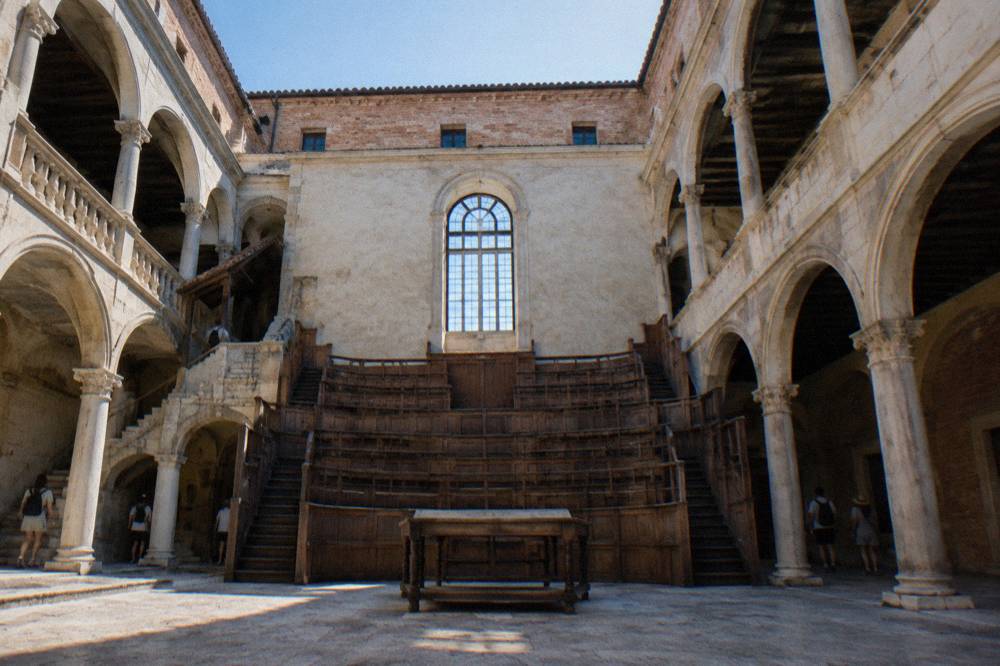 A wooden tiered anatomical theatre with a central table under a high window
