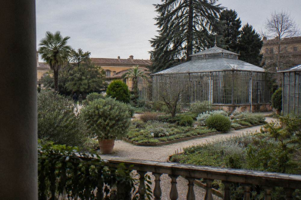 A historic botanical garden with brick paths, green beds and an old glasshouse
