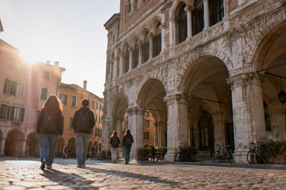 Students crossing a cobbled square beside a Renaissance palace facade in Padua