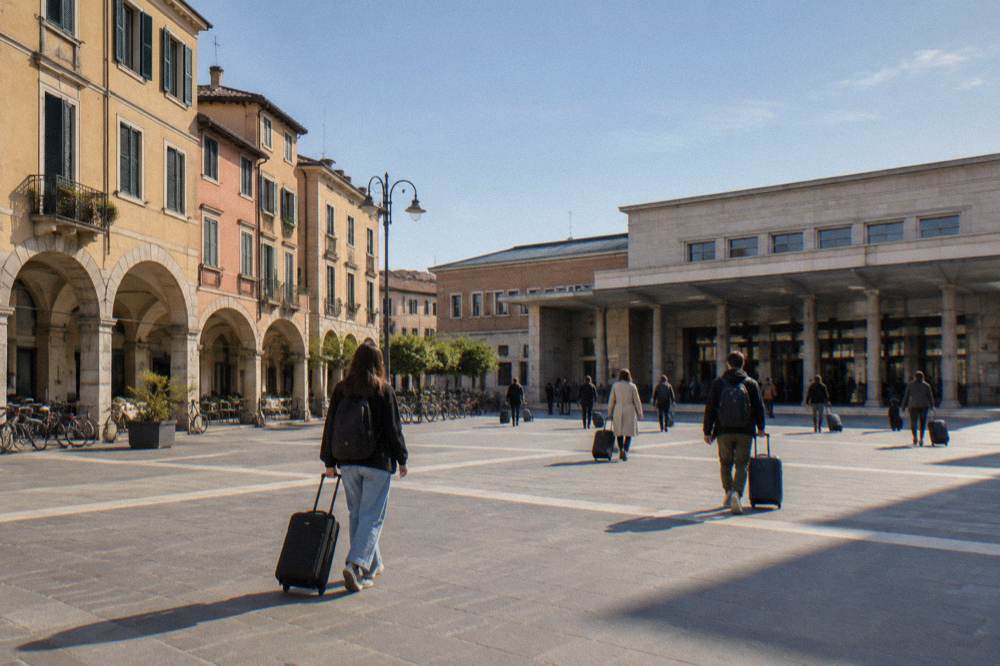 Travellers with suitcases crossing the open forecourt in front of Padua railway station