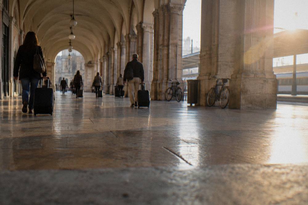 Travellers with suitcases walking through the vaulted concourse of Padua railway station