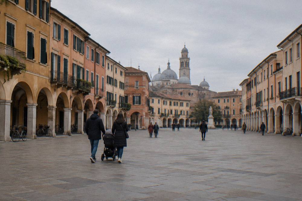 Family with a stroller walking across a wide square in Padua on a level paved surface