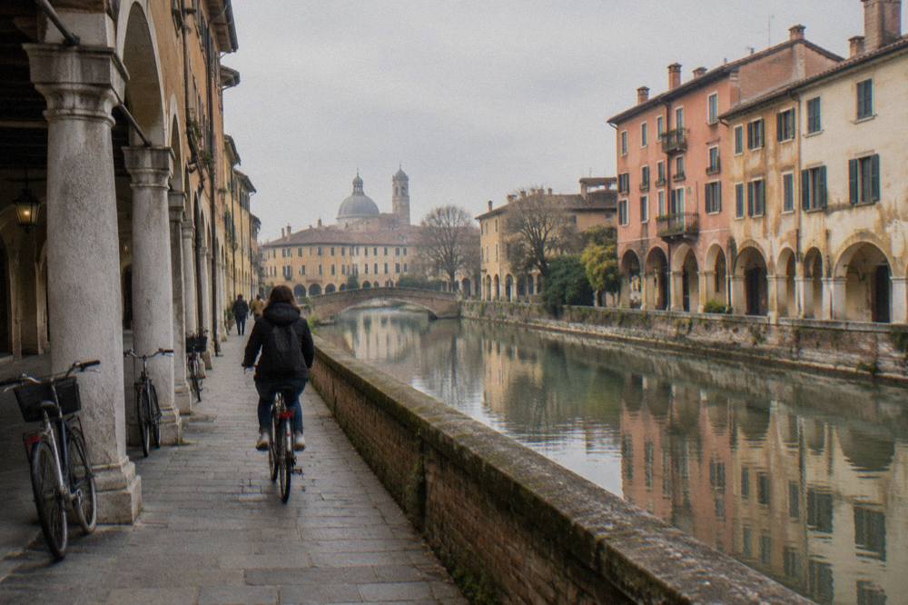 A cyclist riding along a canal-side path in Padua