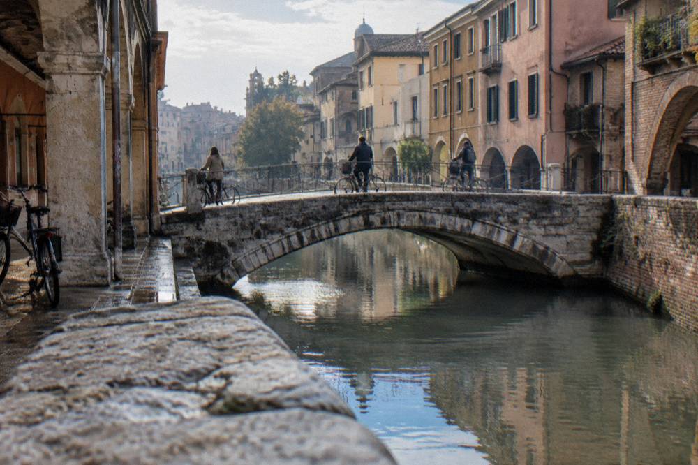 Cyclists crossing a bridge over the Bacchiglione river in Padua