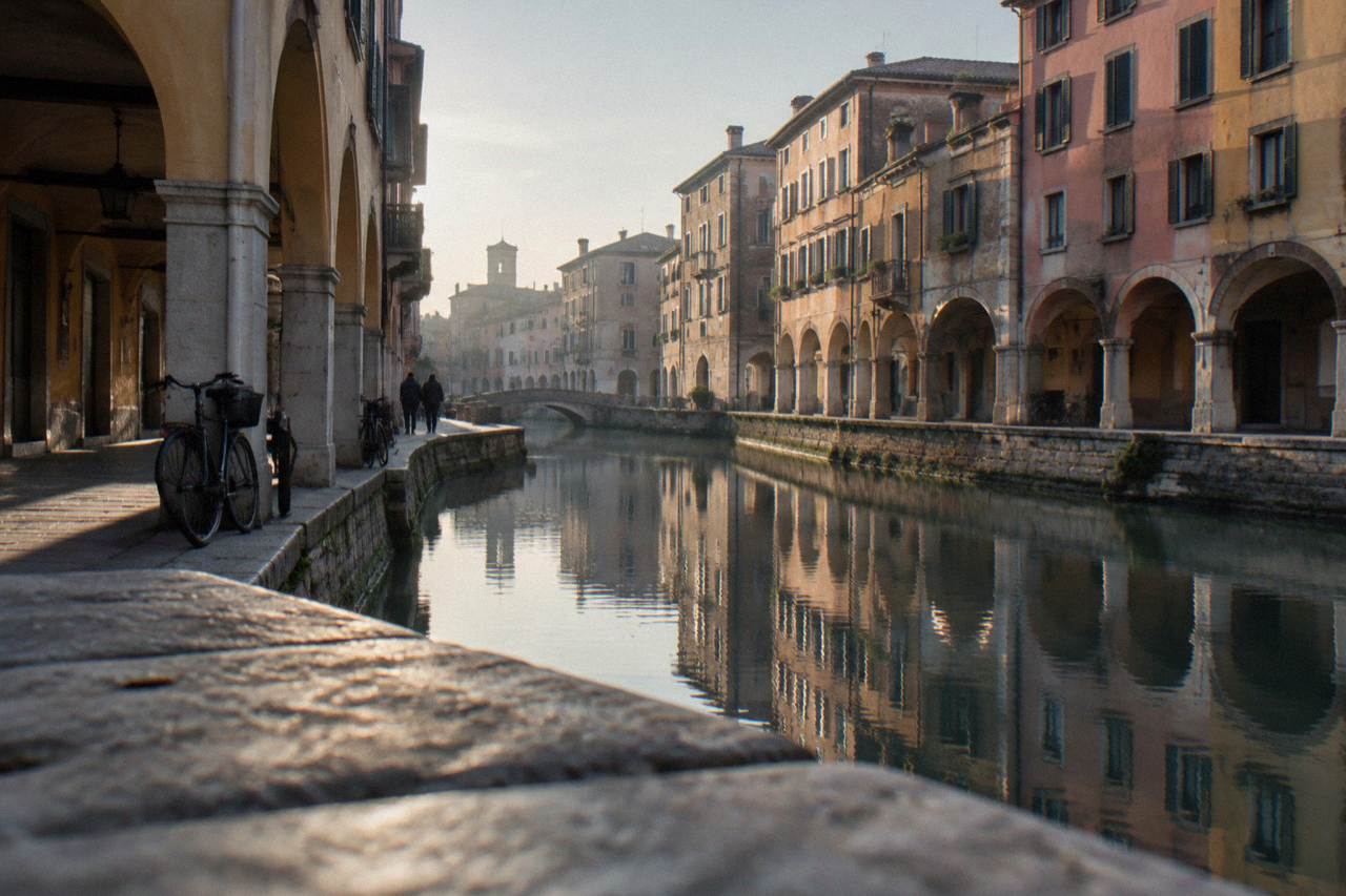 A quiet canal in Padua reflecting old arcaded buildings under an evening sky