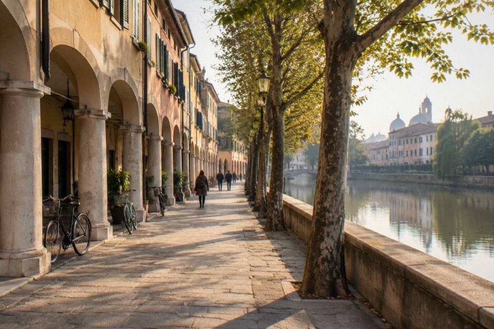 A tree-lined riverside path on the edge of Padua at golden hour