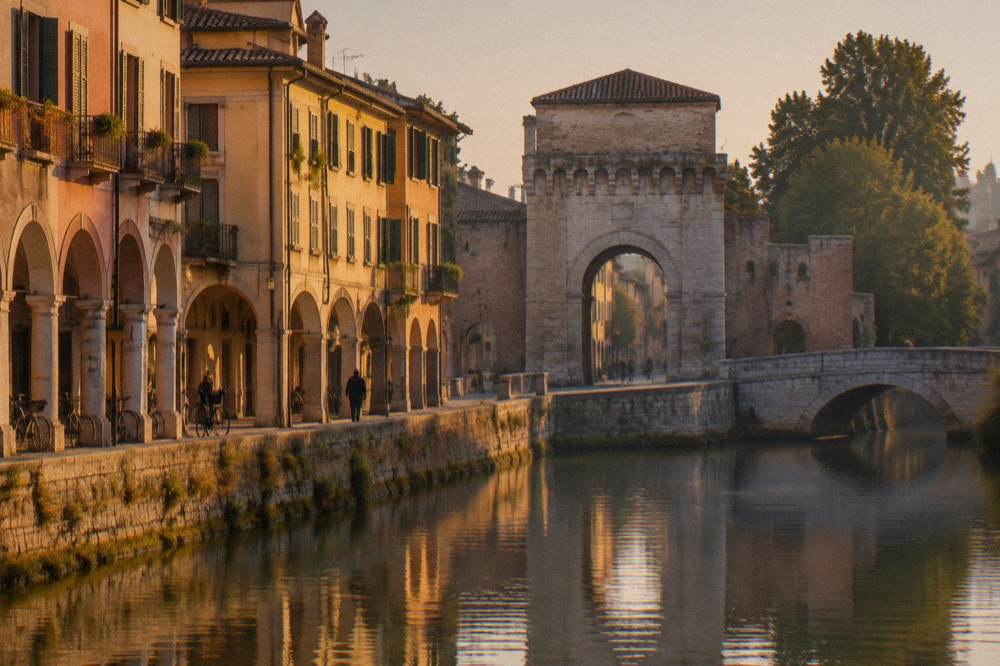 An old stone riverside city gate in Padua seen across water