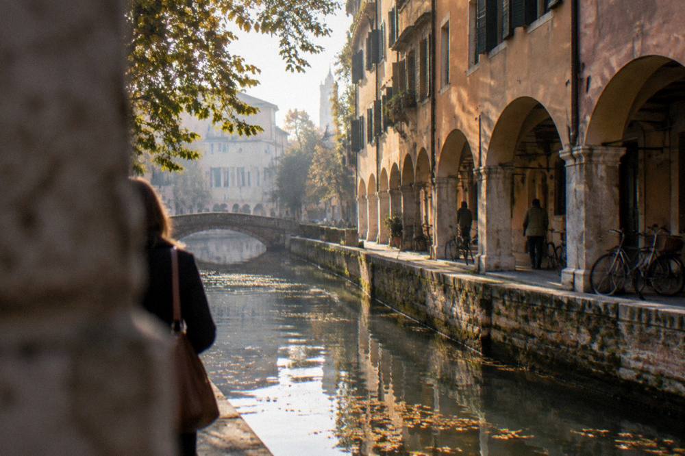 A canal in Padua in soft autumn light with leaves on the water surface