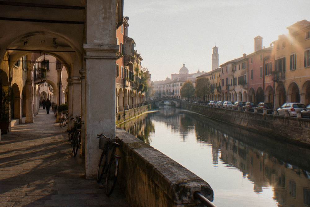 Cars parked along a canal embankment outside Padua's historic centre