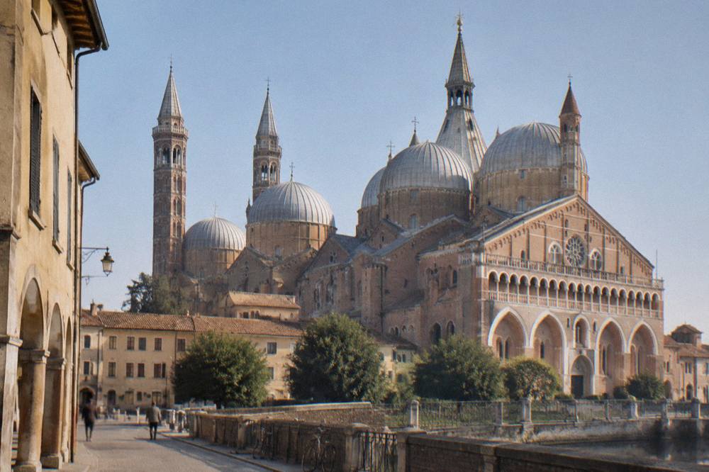 The brick facade and domes of the Basilica of Saint Anthony under a clear sky