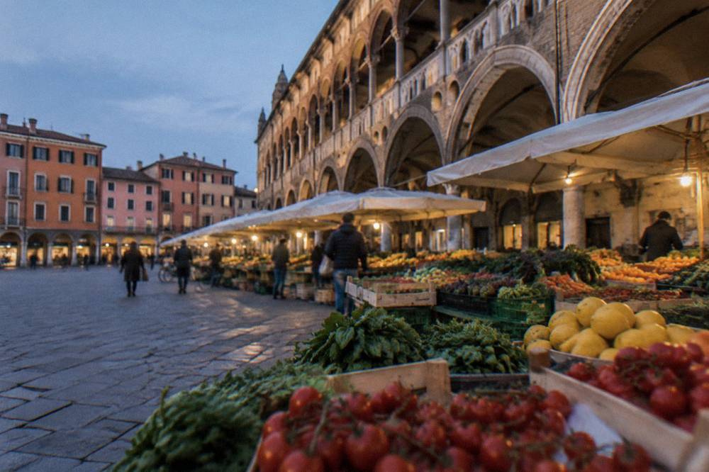 Colourful produce stalls beneath the medieval arcades of a Padua market square