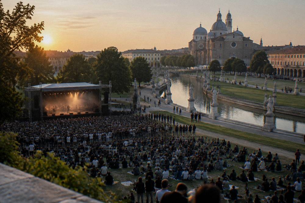 An open-air concert crowd in front of a stage at dusk in a city park