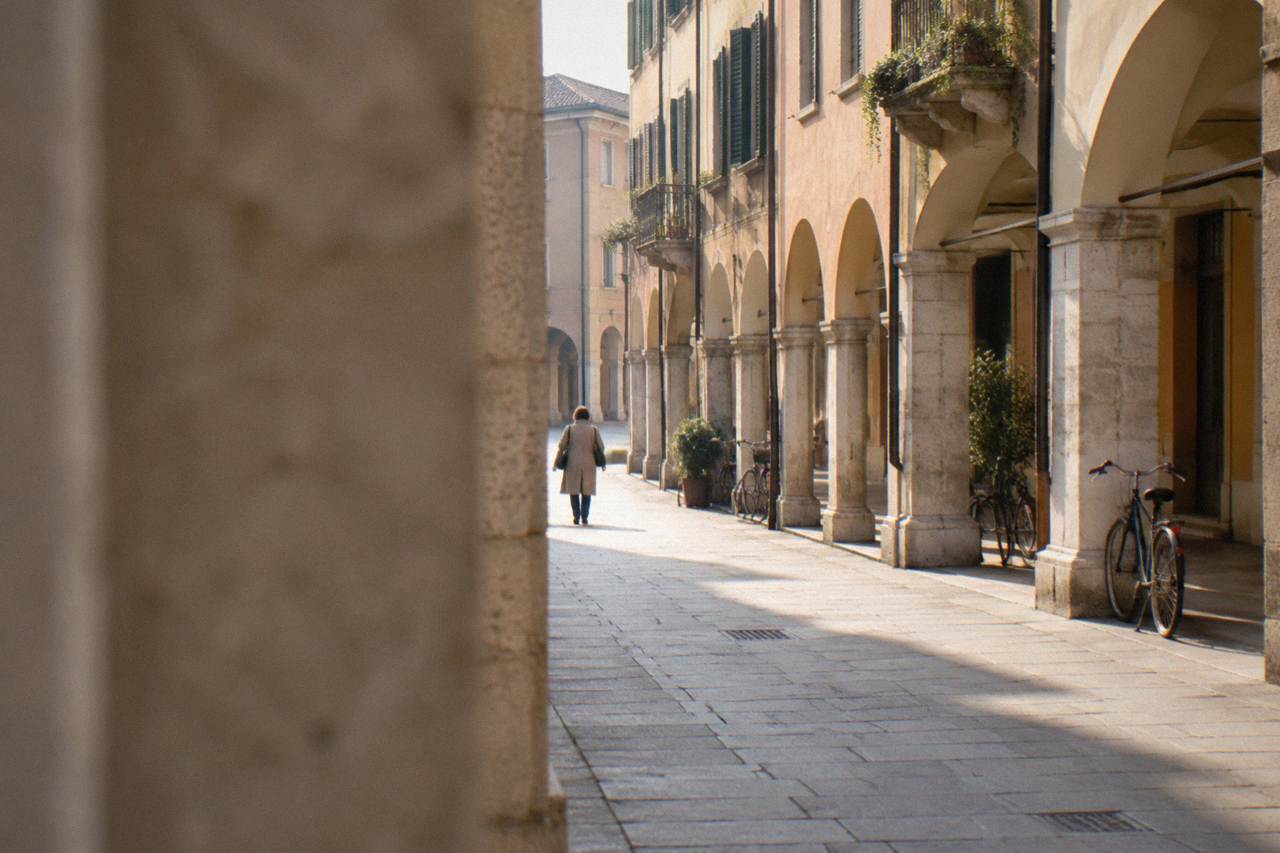 A quiet arcaded street in Padua's historic centre with pale ochre facades and an empty morning light