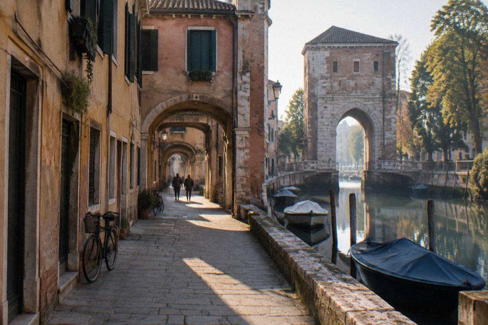 A stone river gate beside a calm canal with moored small boats and trees