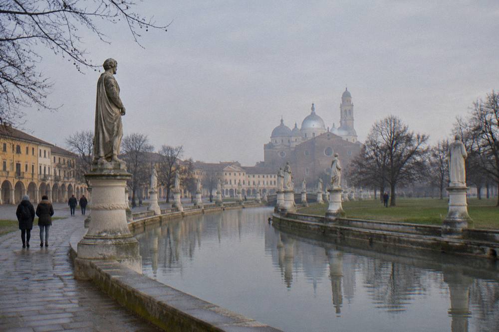 Bare winter trees lining the canal and statues around Prato della Valle in Padua