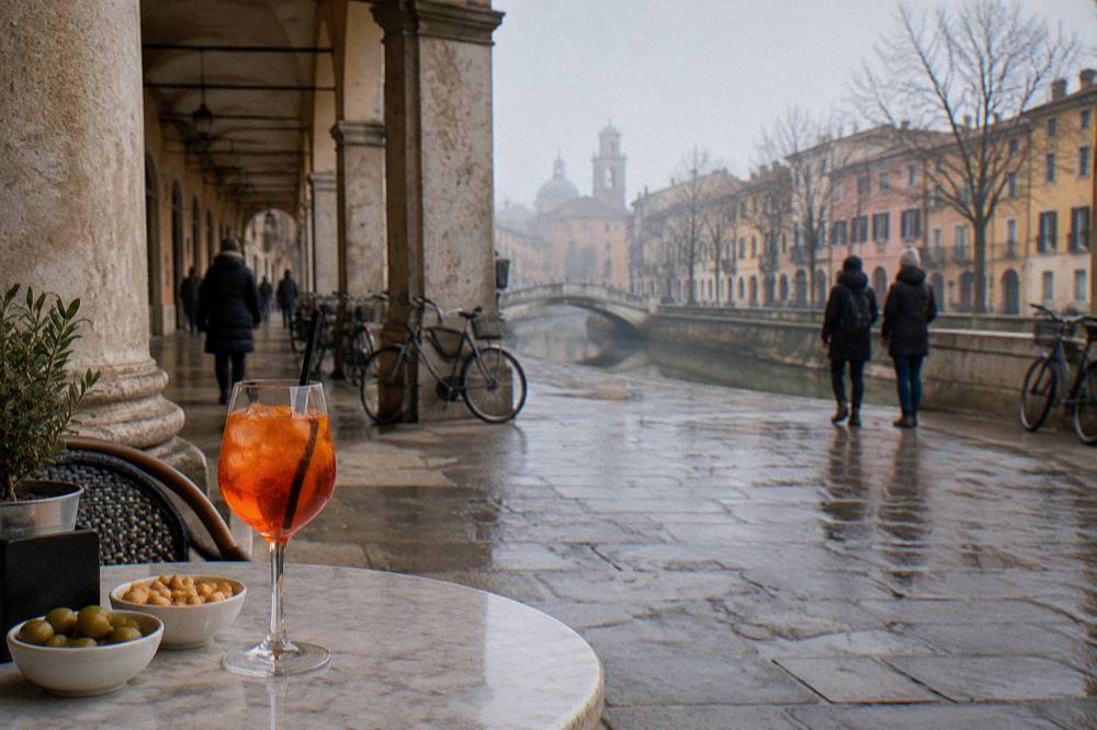 An orange spritz and small snacks on a marble table in an old Padua cafe