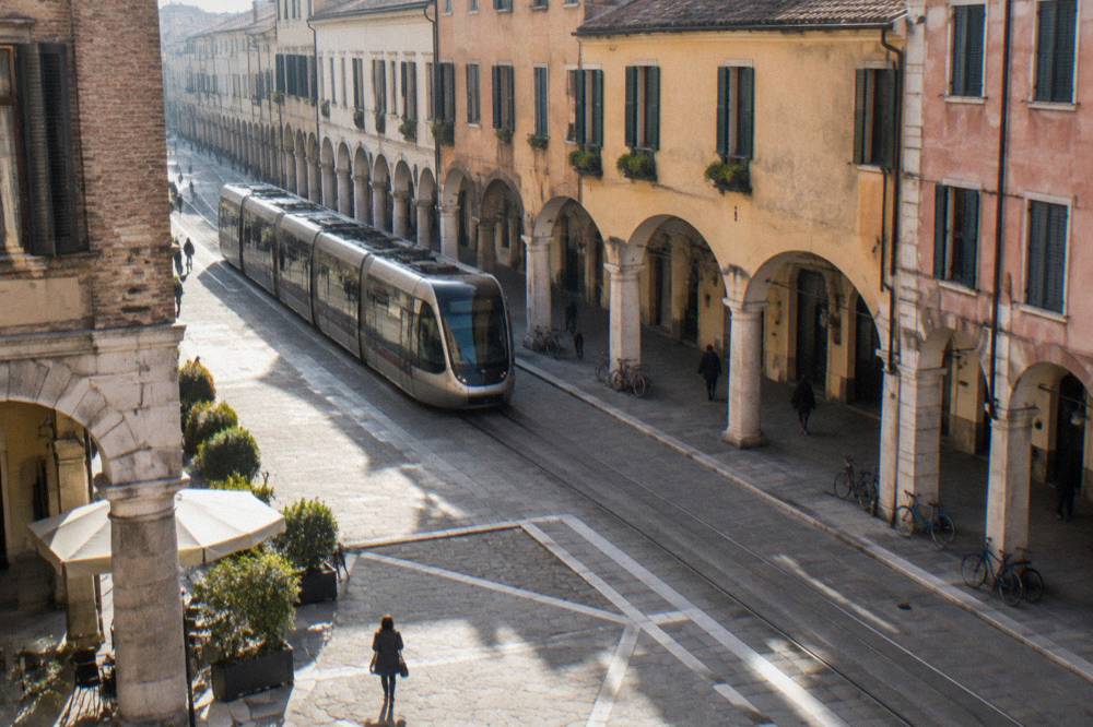 A modern tram passing along a street of arcaded buildings in central Padua