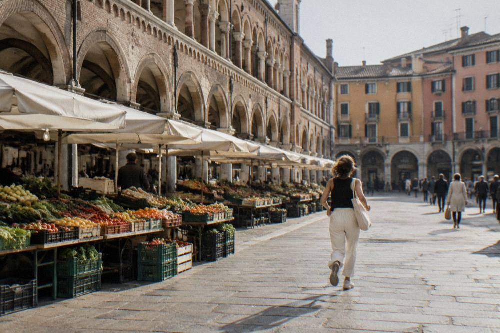 Arcaded market square in Padua with fruit and vegetable stalls under medieval porticoes