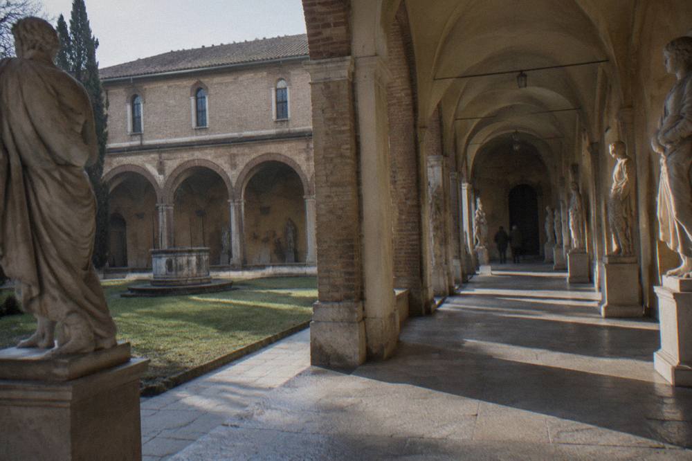Classical sculpture gallery with stone statues lining both sides of an arched hall