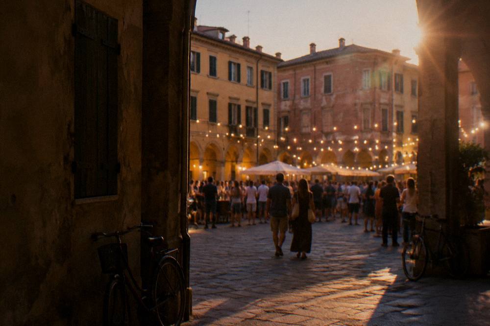 A crowd gathered in an Italian square at night during a festival with warm lights strung between buildings