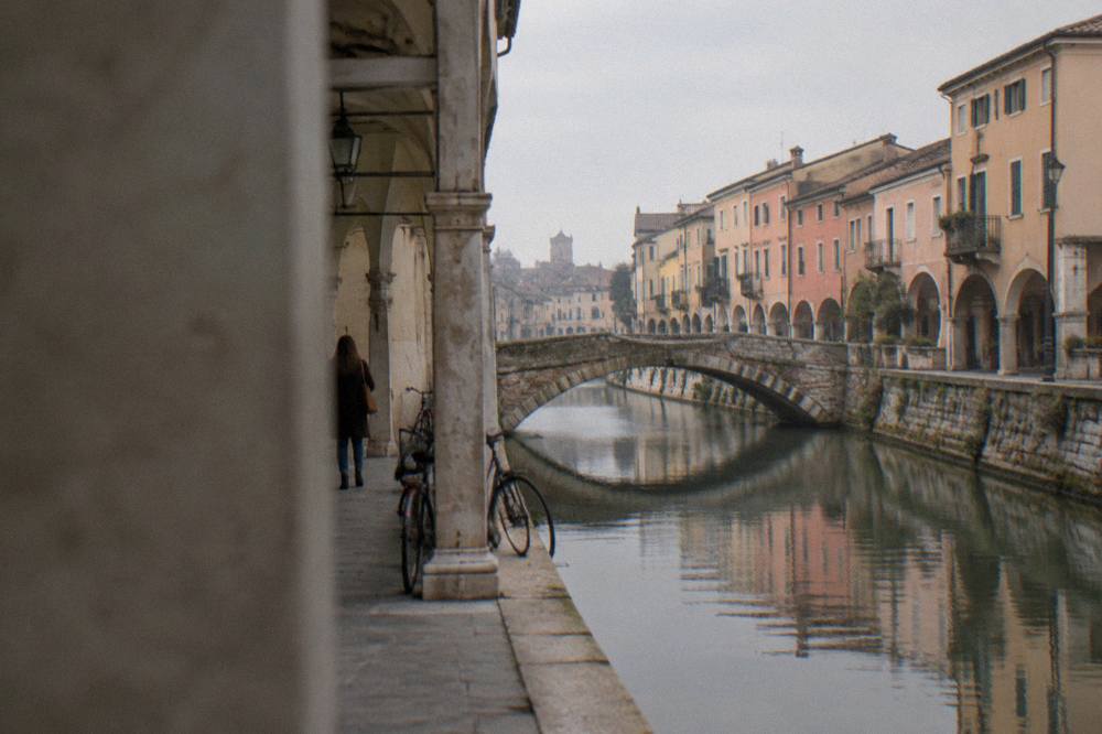 Canal in Padua with a stone bridge and pastel facades along the water