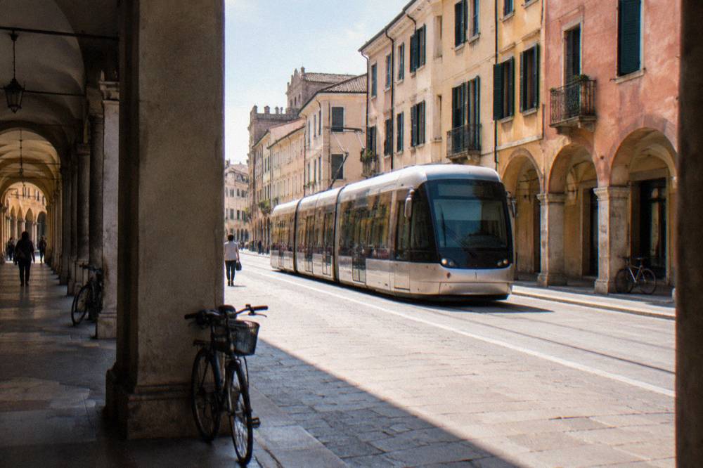 Tram travelling along a Padua street with historic buildings behind it