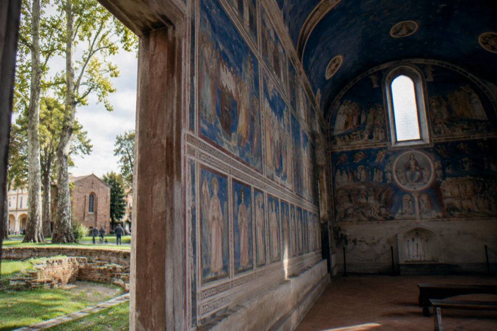 The blue frescoed interior of the Scrovegni Chapel with figures painted along the walls