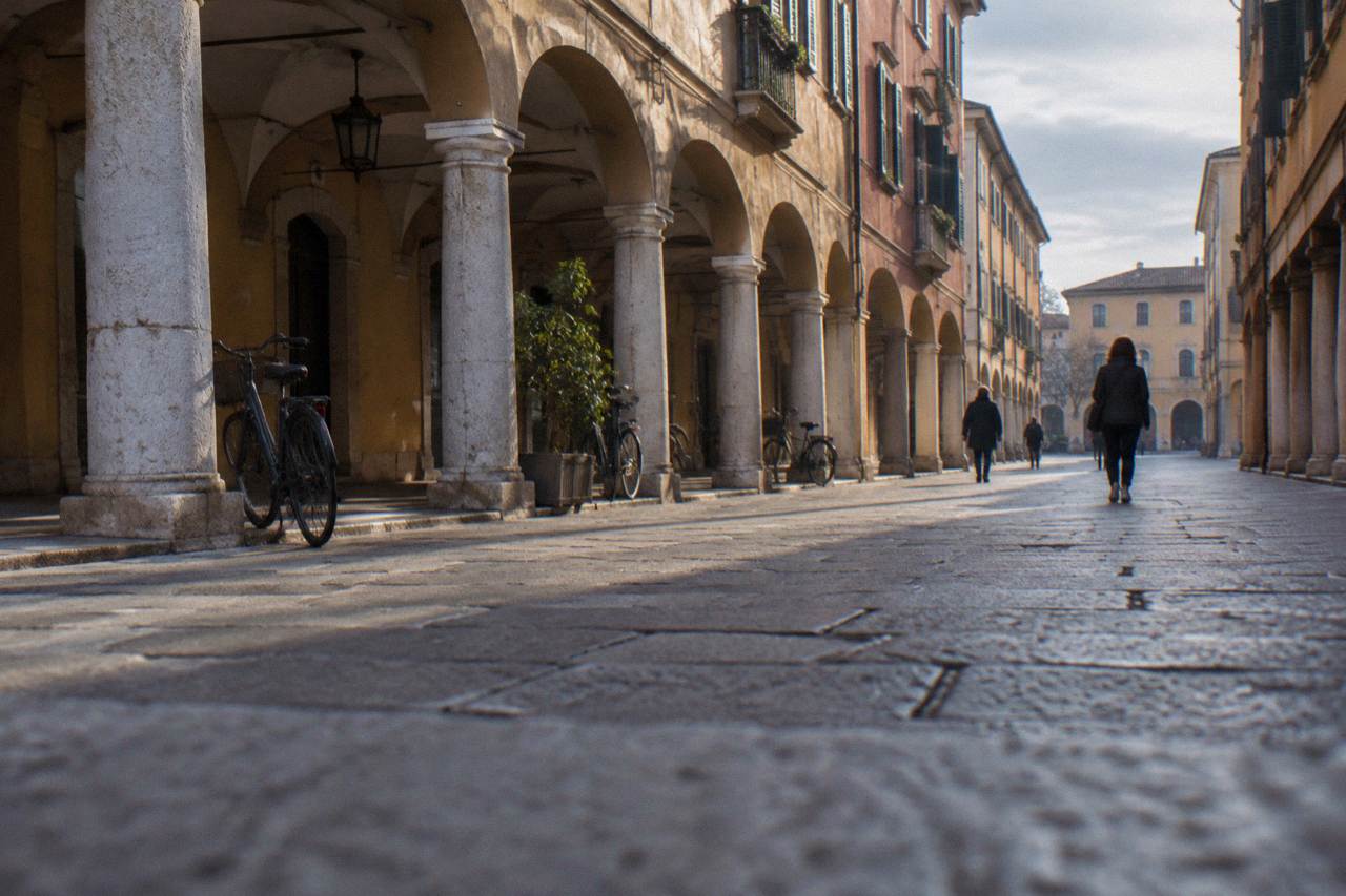 Arcaded street in Padua under a cloudy sky with a few people walking