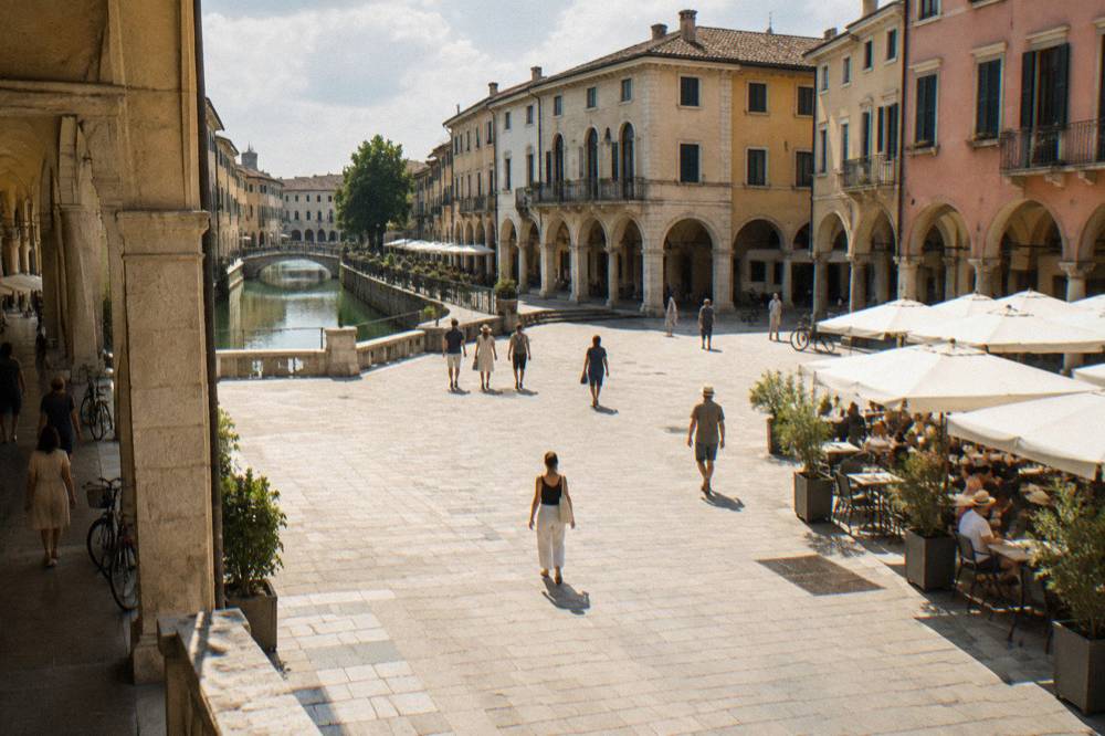 Sunlit piazza in Padua in summer with shaded arcades and cafe tables