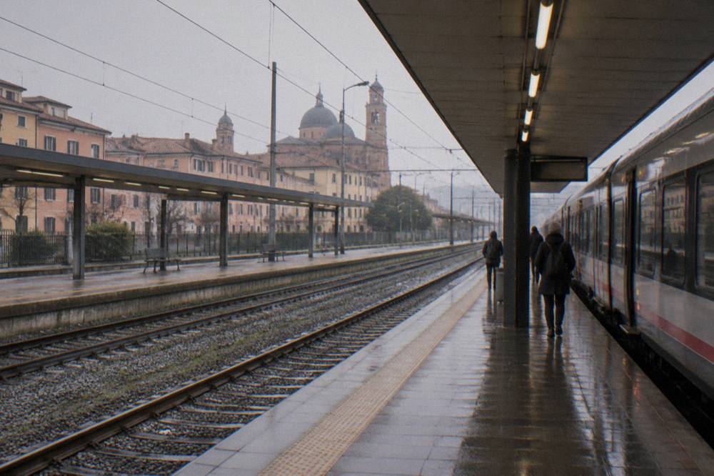 Train platform at Padua station on an overcast day with a train waiting