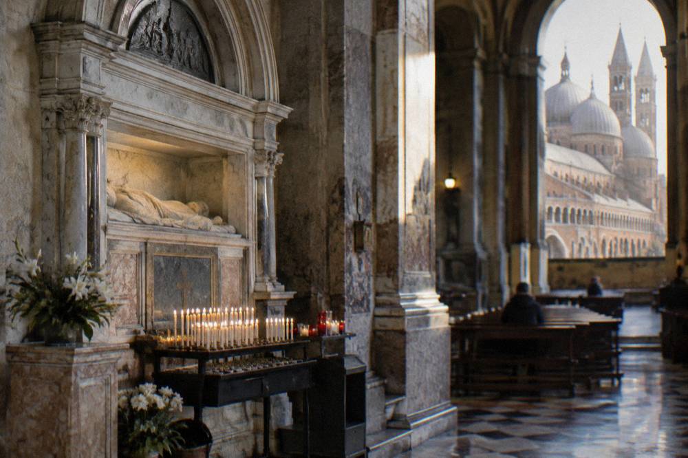 A marble tomb chapel with candle offerings inside a large basilica