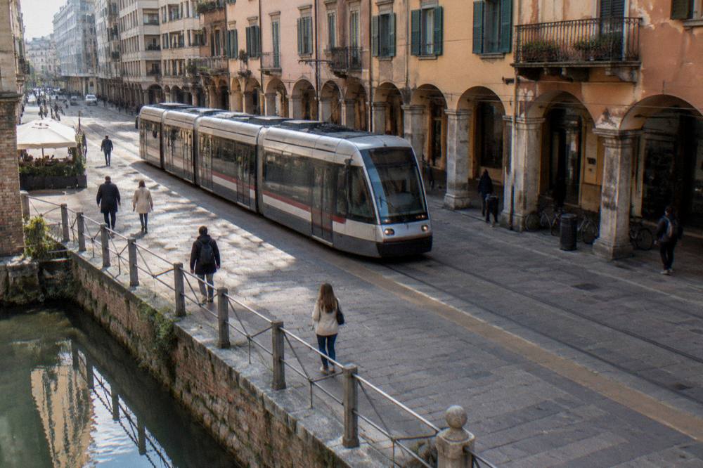 A tram passing modern buildings on a street in Padua