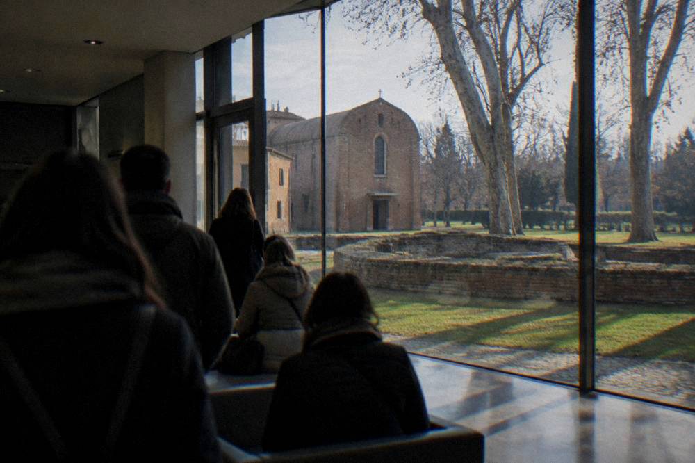 Visitors waiting in a modern climate-control room before entering a frescoed chapel