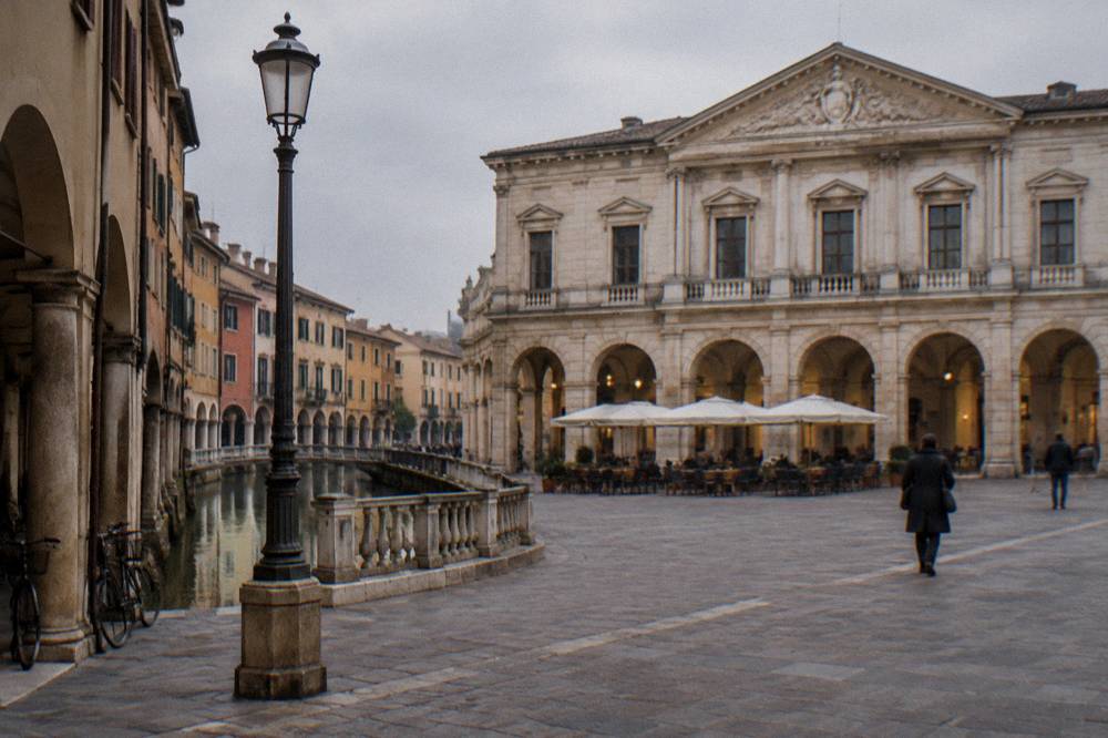 The neoclassical facade of a historic cafe building in Padua seen across a square in late afternoon light